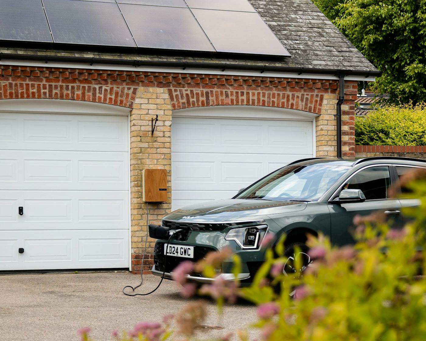Brick house with a solar roof and an electric car charging on the driveway