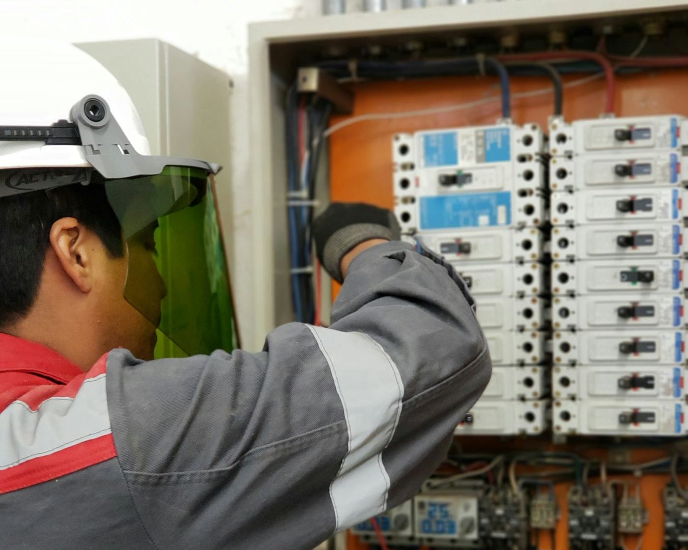 Phoenix engineer in safety gear testing a distribution board with a multimeter