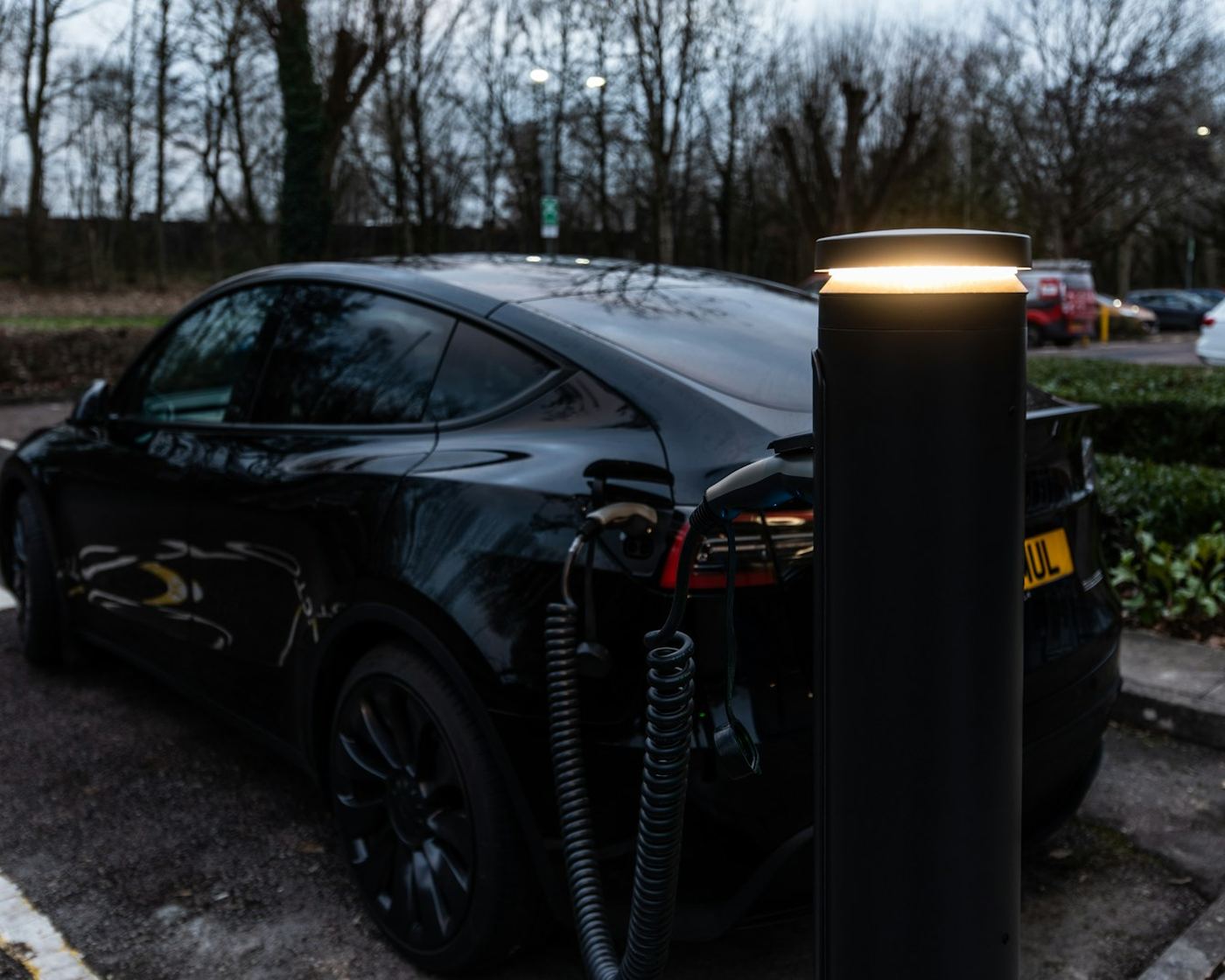 Electric car charging at a pedestal charger in a workplace car park