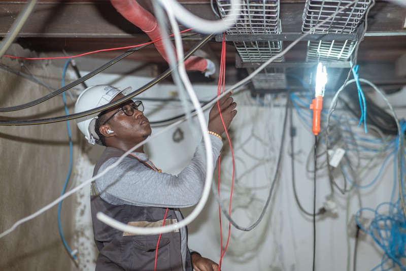 Electrician working under a lamp to repair ceiling wiring on an emergency call-out